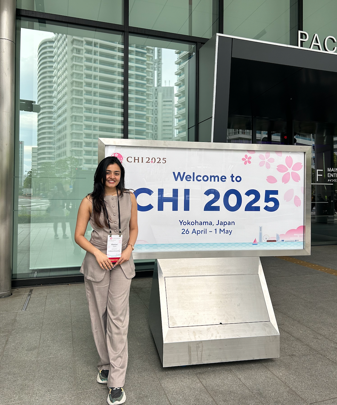 Kasturi standing beside the CHI 2025 welcome sign in Yokohama, Japan