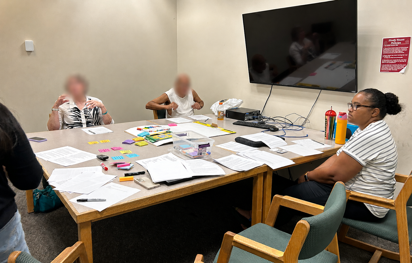 In-person research session with older adult participants seated around a table. Participant faces are blurred for privacy.